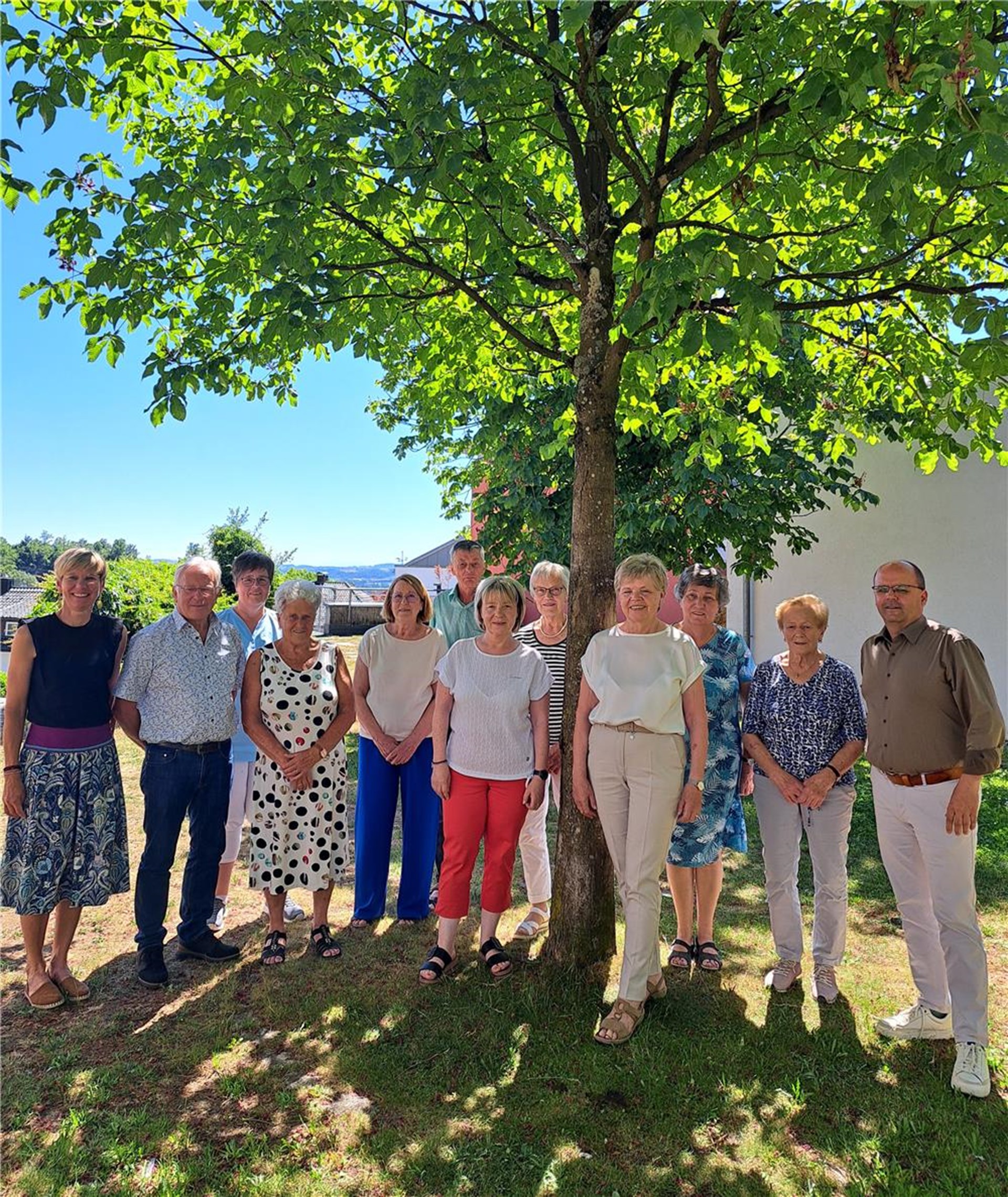 Eine Gruppe von Menschen steht vor einem Baum und posiert für ein Foto.